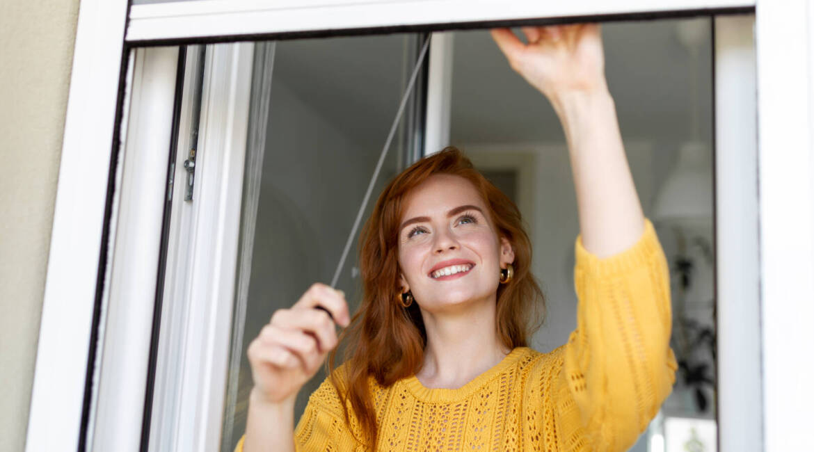 Woman hand hold retractable pleated insect screen holder to open or close the window ,mosquito nets